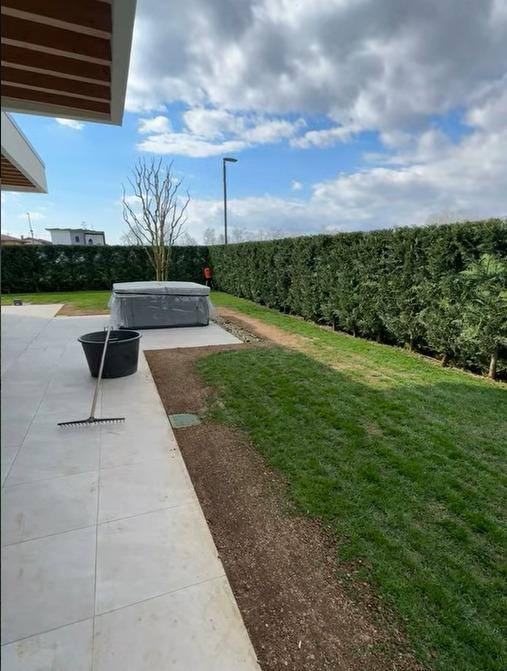 Giardino appena finito: prato nuovo, siepe di lauro appena piantata e attrezzi ancora sul posto